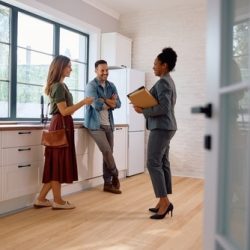 Happy,Couple,Talking,With,Real,Estate,Agent,While,Buying,New